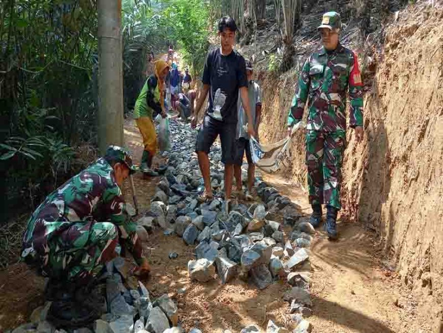 Babinsa Koramil 11 Punggelan Melaksanakan Karya Bakti Pengerasan Jalan Usaha Tani